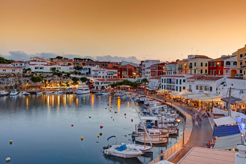 Traditional fishing boats moored in a Menorca harbor at sunset, Balearic Islands, Spain
