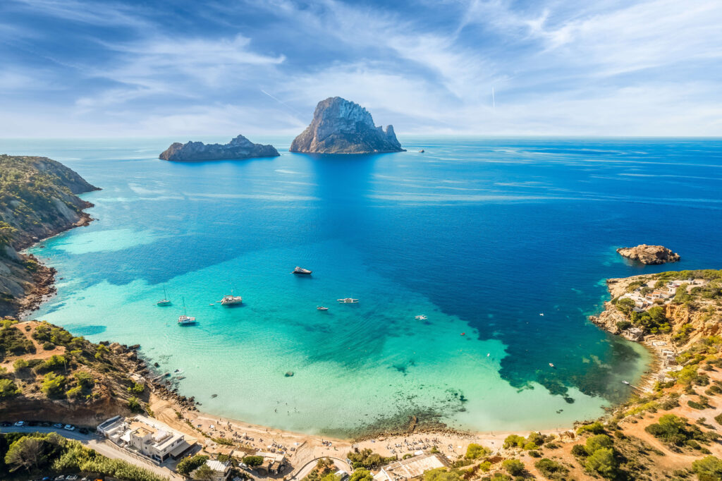 Yachts anchored in the turquoise bay of Cala d'Hort beneath Es Vedrà, Ibiza